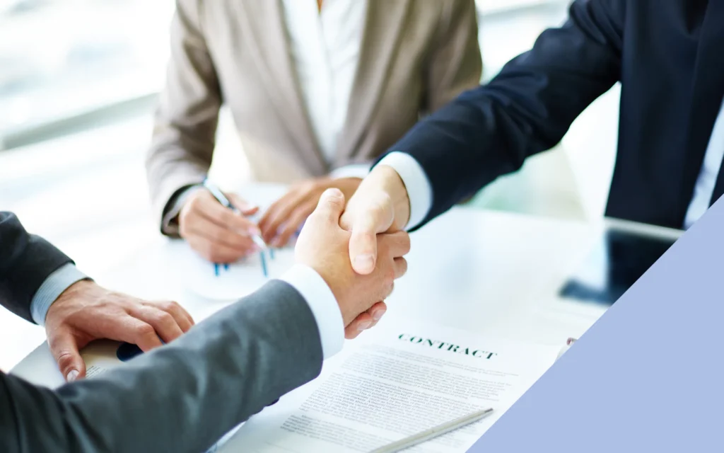 Plano de dos hombres dándose la mano para firmar un contrato